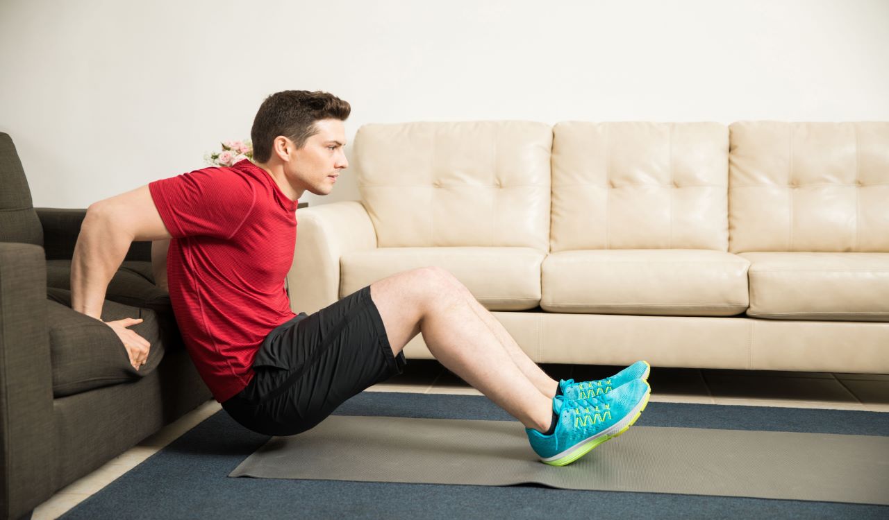 Man performing tricep dip by using his couch for an easy workout.