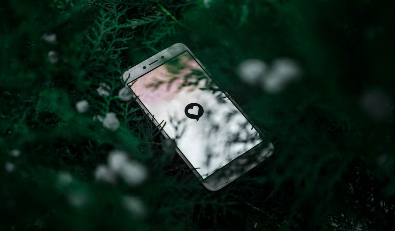 Phone in grass with a heart on the screen