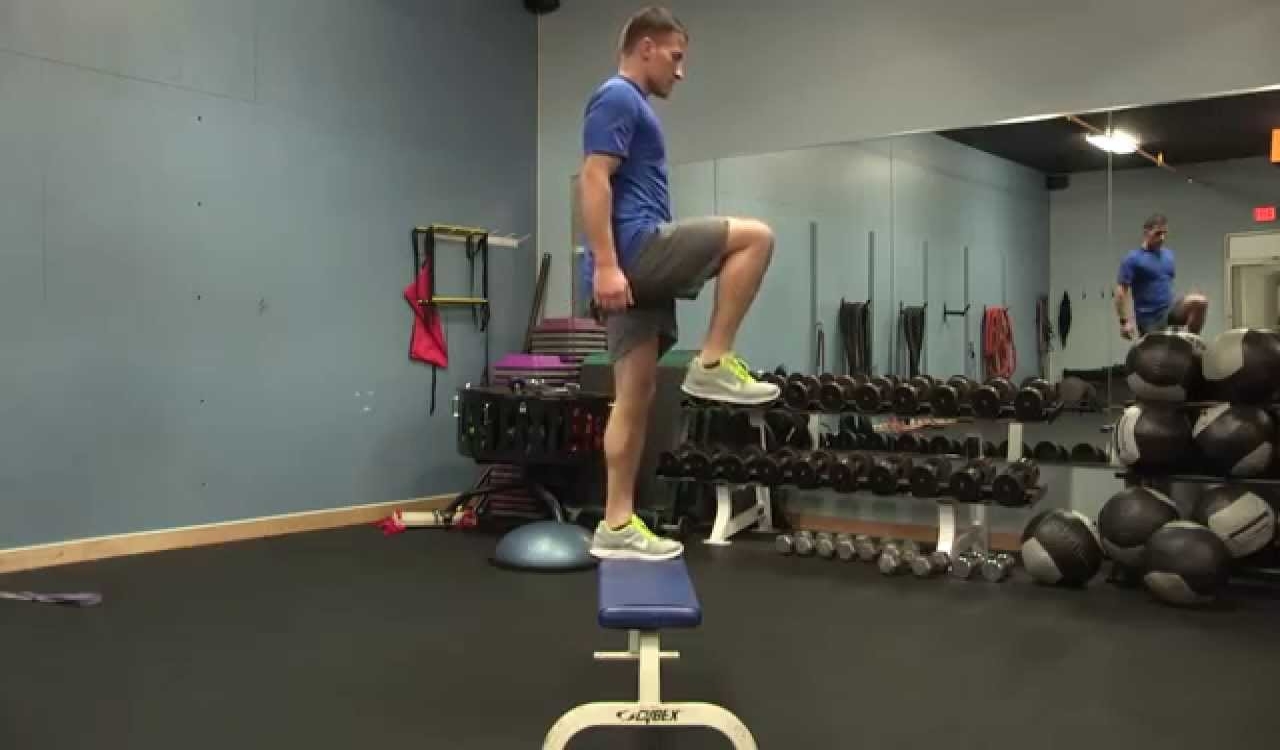 Man performing the easy workout step up high knee and using a bench